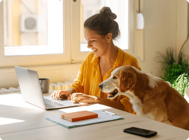 Dame med hund ser på økonomien på PC med Kan